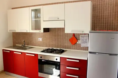 a kitchen with red cabinets and a white refrigerator at Appartamento Calvino piano terra in via Mulino 31 in San Vito lo Capo