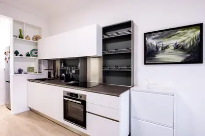 a kitchen with white cabinets and black appliances at A due passi dal mare in Palermo