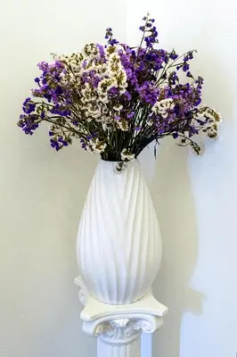 a white vase with purple and white flowers in it at Casa Botanica Apartment in Palermo