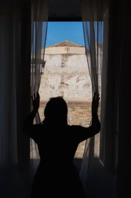 a silhouette of a woman looking out a window at Casabea in Palermo