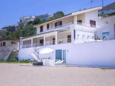 a white house on the beach with chairs and an umbrella at Apartment Villa am Meer Trappeto by Interhome in Trappeto