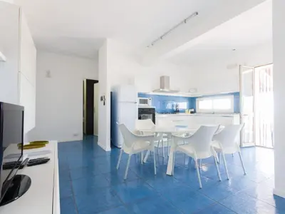 a white kitchen with a table and white chairs at Apartment Villa am Meer Trappeto by Interhome in Trappeto