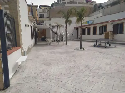 a courtyard with benches and palm trees in a building at Apartment Ferienhäuser Small App- für 5 in Balestrate by Interhome in Balestrate