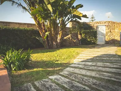a walkway with a white door and a palm tree at Apartment Wohnung GIallo mit Schwimmbad und Meerblick by Interhome in Balestrate