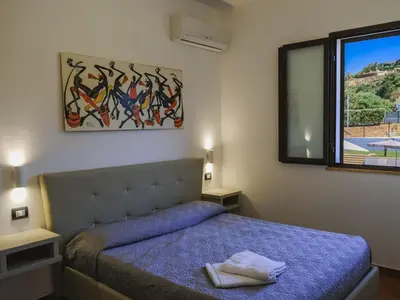 a bedroom with a bed and a mirror and a window at Apartment Lila Wohnung mit Schwimmbad und Meerblick by Interhome in Balestrate