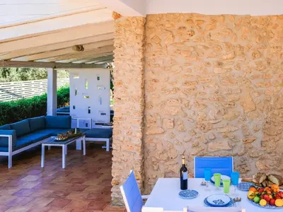 a patio with a stone wall and a table and chairs at Apartment Wohnung in Balestrate mit Schwimmbad und Meerblick by Interhome in Balestrate