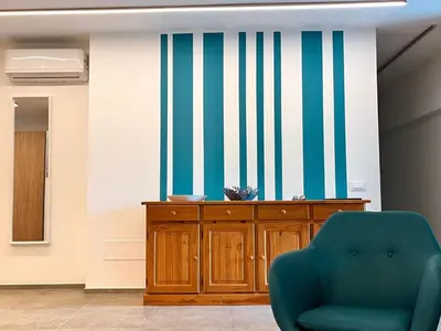 a living room with a blue chair and striped wall at Apartment Villa Sao- Scopello- Punta Pispisa by Interhome in Scopello