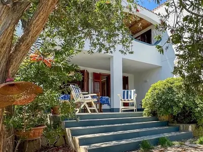 a white house with blue chairs and stairs at Apartment Villa Sao- Scopello- Punta Pispisa by Interhome in Scopello