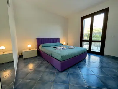 a bedroom with a purple bed and a large window at Apartment Casa Sterlizia bei Holiday World by Interhome in San Vito lo Capo