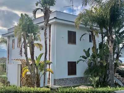 a white house with palm trees in front of it at Apartment Wohnung Glicine mit Schwimmbad und Meerblick by Interhome in Balestrate