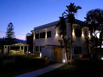 a house with lights on the side of it at night at Apartment Wohnung Glicine mit Schwimmbad und Meerblick by Interhome in Balestrate