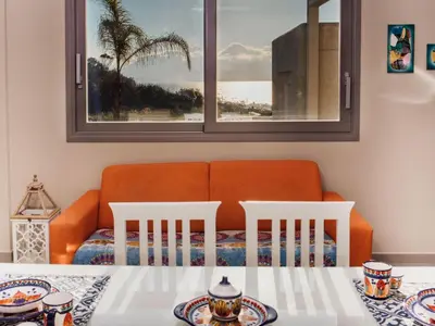 a living room with an orange couch and a table and chairs at Holiday Home Haus in Balestrate mit privatem Parkplatz by Interhome in Balestrate