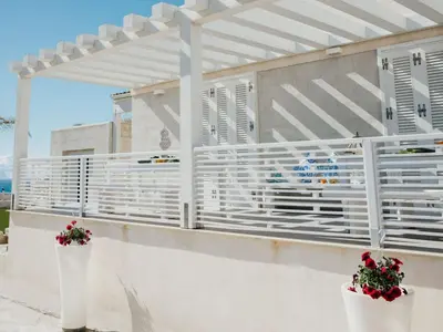 a white pergola on a white wall with two plants at Holiday Home Haus in Balestrate mit privatem Parkplatz by Interhome in Balestrate