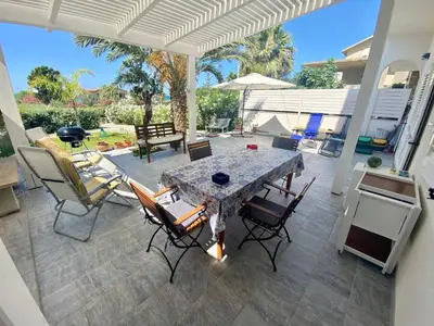 a patio with a table and chairs on a patio at Holiday Home Villa Oasi- 50 m vom Strand entfernt- klimatisiert by Interhome in Alcamo