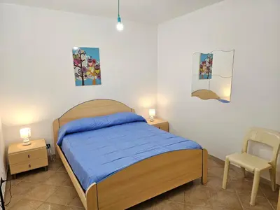 a bedroom with a bed and two tables and a chair at Holiday Home Villa mit Wasserblick by Interhome in Campofelice di Roccella