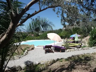 a pool with chairs and umbrellas on a beach at Holiday Home Manderino-Panoramasuite mit Park und Pool by Interhome in Santa Flavia