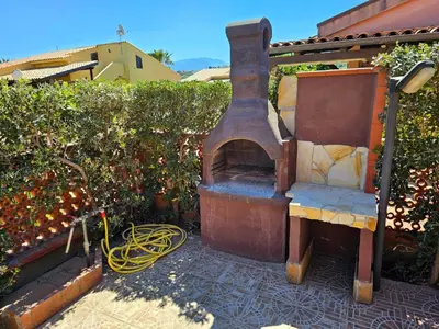an outdoor oven sitting on a patio next to a hedge at Holiday Home Ferienvilla mit Wasserblick by Interhome in Campofelice di Roccella