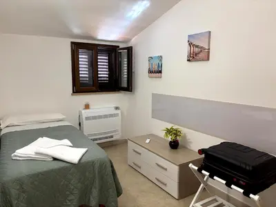a bedroom with a bed and a chair with a suitcase at casa 3 nodi in Carini