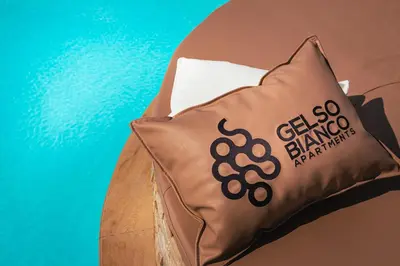 a brown pillow on a bed with a blue background at Gelso Bianco Collection Apartments in Campofelice di Roccella