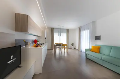 a living room with a blue couch and a kitchen at Gelso Bianco Collection Apartments in Campofelice di Roccella