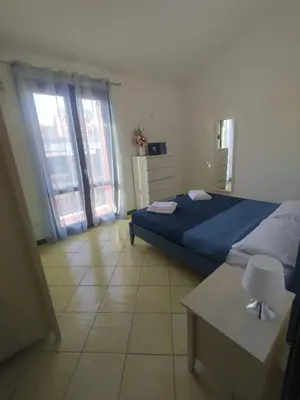 a bedroom with a bed and a table and windows at Casa di Lolli in San Vito lo Capo