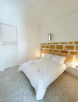 a white bed in a room with a brick wall at Brezza Marina apartment in Carini