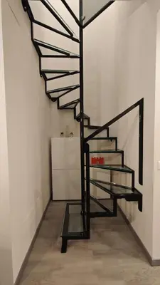 a black spiral staircase in a white room at Profumo di casa 2 in Lascari