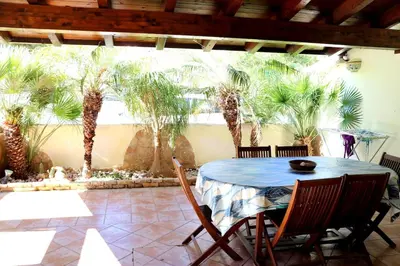 a patio with a table and chairs and palm trees at Villetta Gelsomini, San Vito Lo Capo in San Vito lo Capo