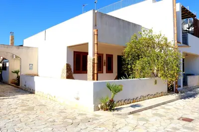 a white house with a white wall and trees at Villetta Gelsomini, San Vito Lo Capo in San Vito lo Capo