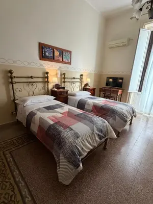 a bedroom with a bed and a window and a chandelier at Albergo Cavour in Palermo