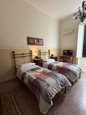 a bedroom with two beds and two tables and a television at Albergo Cavour in Palermo