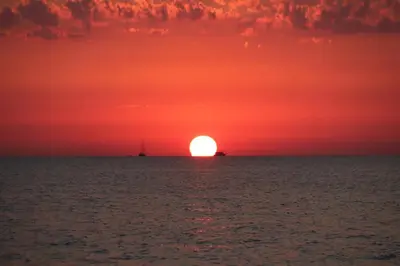 a sunset over the ocean with a boat in the distance at Cala38 in Terrasini