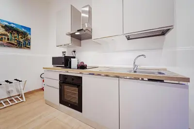 a kitchen with white cabinets and a sink at Maison Vulpi in Palermo