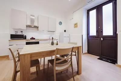 a kitchen and dining room with a wooden table and chairs at Maison Vulpi in Palermo