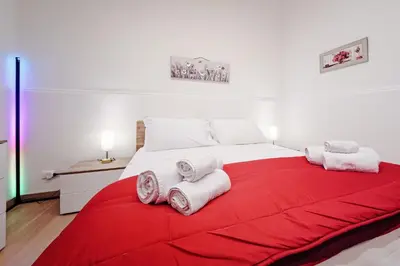 a large white bed with towels on a red blanket at Maison Vulpi in Palermo