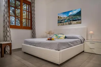 a bedroom with a white bed in a room at Villa Giummara Cala bianca in Castellammare del Golfo