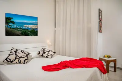 a bedroom with a bed with a red blanket on it at Villa Giummara Cala bianca in Castellammare del Golfo