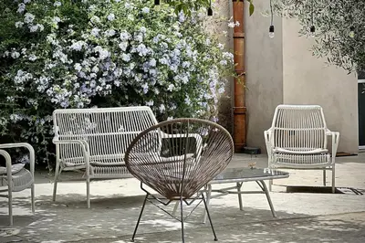 three chairs and a table in front of a bush with flowers at Villa Halcón, casale con piscina tra gli ulivi, vicino al mare tra Balestrate e Alcamo in Partinico