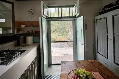 a kitchen with a window and a bowl of grapes at Villa Halcón, casale con piscina tra gli ulivi, vicino al mare tra Balestrate e Alcamo in Partinico
