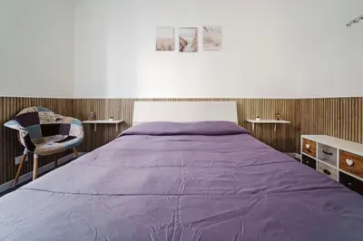 a bedroom with a large purple bed and a chair at La Casetta di Simo & Leo in Palermo