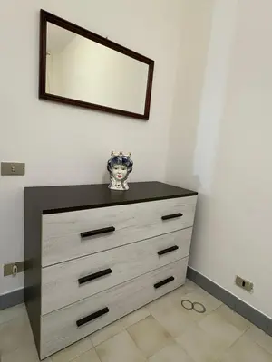 a dresser in a room with a mirror on the wall at Delle Palme Holiday Home in Isola delle Femmine