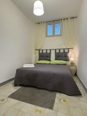a bedroom with a large bed with a window at Delle Palme Holiday Home in Isola delle Femmine