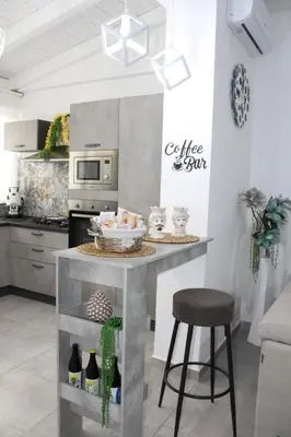 a kitchen with a counter with a table and stool at Villa del sole in Carini