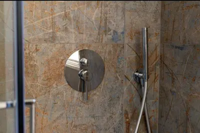 a shower with a round mirror on a stone wall at La Luna di Noah al Massimo in Palermo