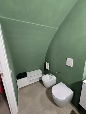 a bathroom with a toilet and a green wall at Venticinque Passi - nel cuore di Palermo in Palermo