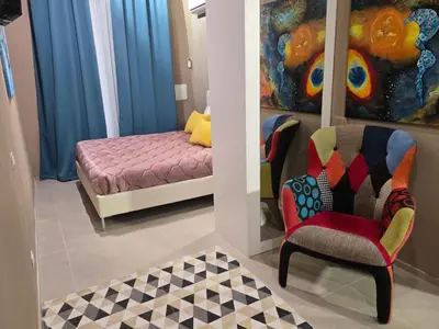 a room with a bed and a chair and a couch at Venticinque Passi - nel cuore di Palermo in Palermo