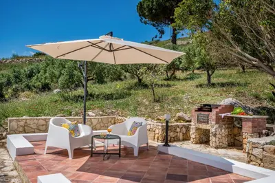 a patio with two chairs and an umbrella at Vista Mare Scopello AC Jacuzzi 3 camere by Proger in Scopello