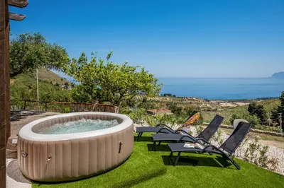 a hot tub in the grass with two chairs at Vista Mare Scopello AC Jacuzzi 3 camere by Proger in Scopello