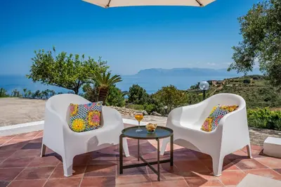 two white chairs and a table with a glass of wine at Vista Mare Scopello AC Jacuzzi 3 camere by Proger in Scopello