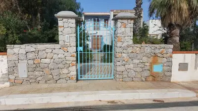a gate in a stone wall in front of a house at Villa La Chiocciola in San Vito lo Capo